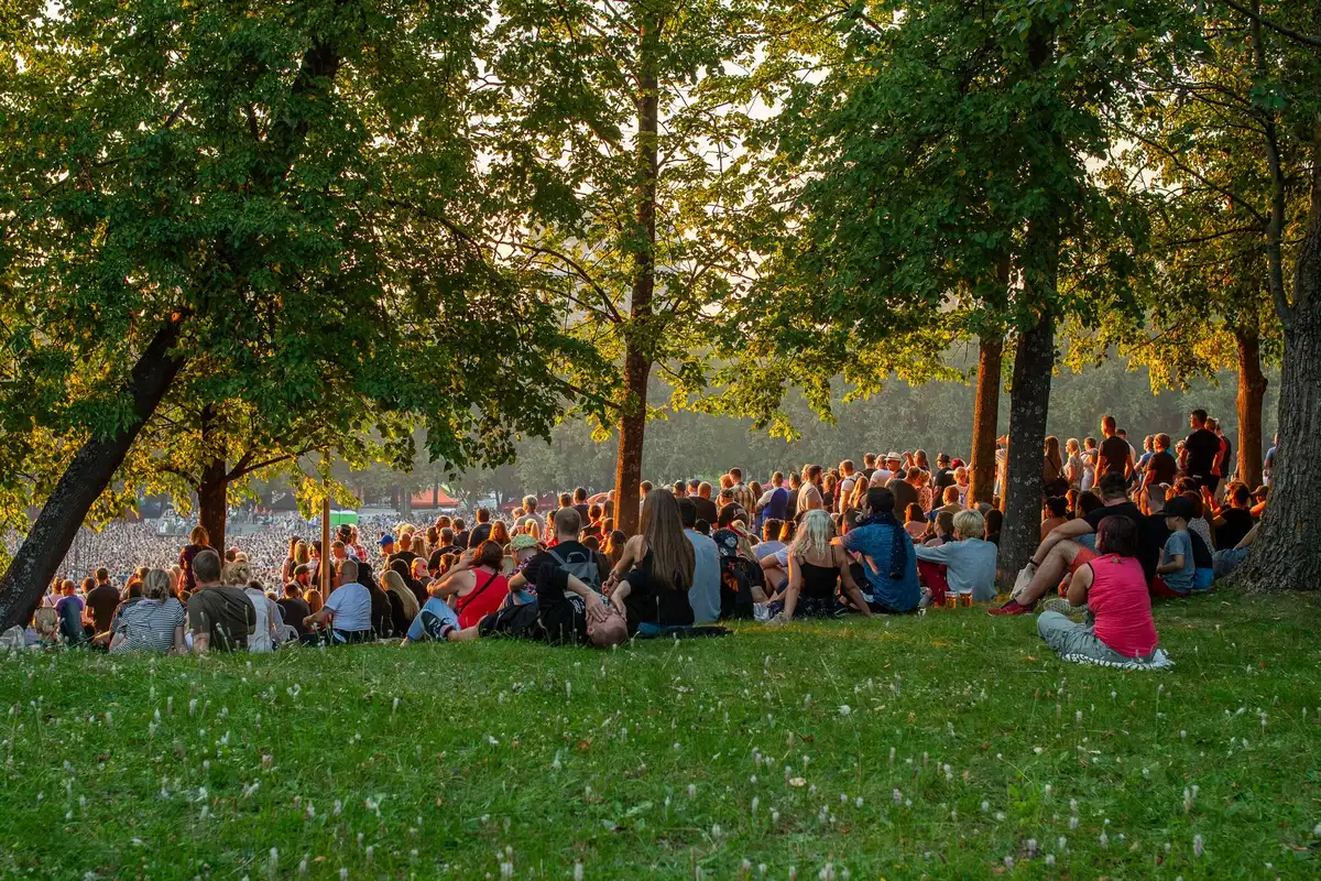 P&uacute;blico sentado na relva a assistir a um concerto ao ar livre durante o ver&atilde;o