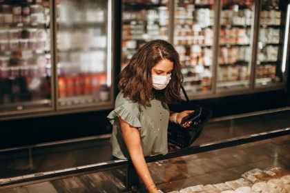 Carrinho de compras cheio de alimentos básicos num supermercado, com recibo de compra visível.