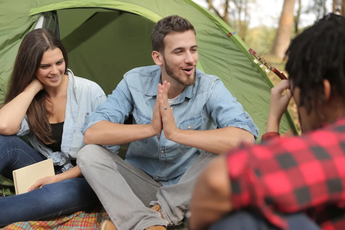 Jovens a montar uma tenda durante um acampamento na natureza