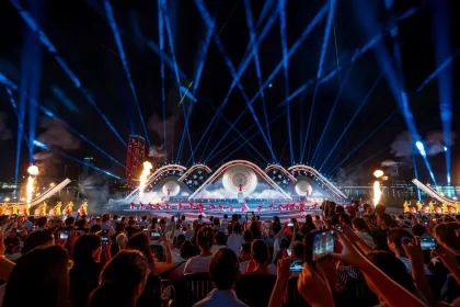 Palco de festival ao ar livre à noite com público e luzes coloridas