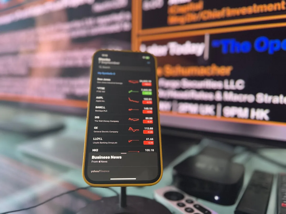 Mão anónima segurando telemóvel com seta de aumento de preço no ecrã