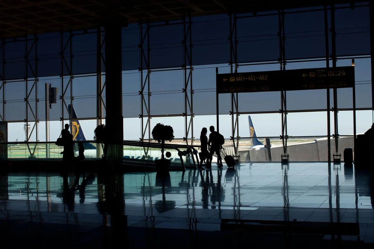 Silhueta de jogador em aeroporto com placas de partida ao fundo