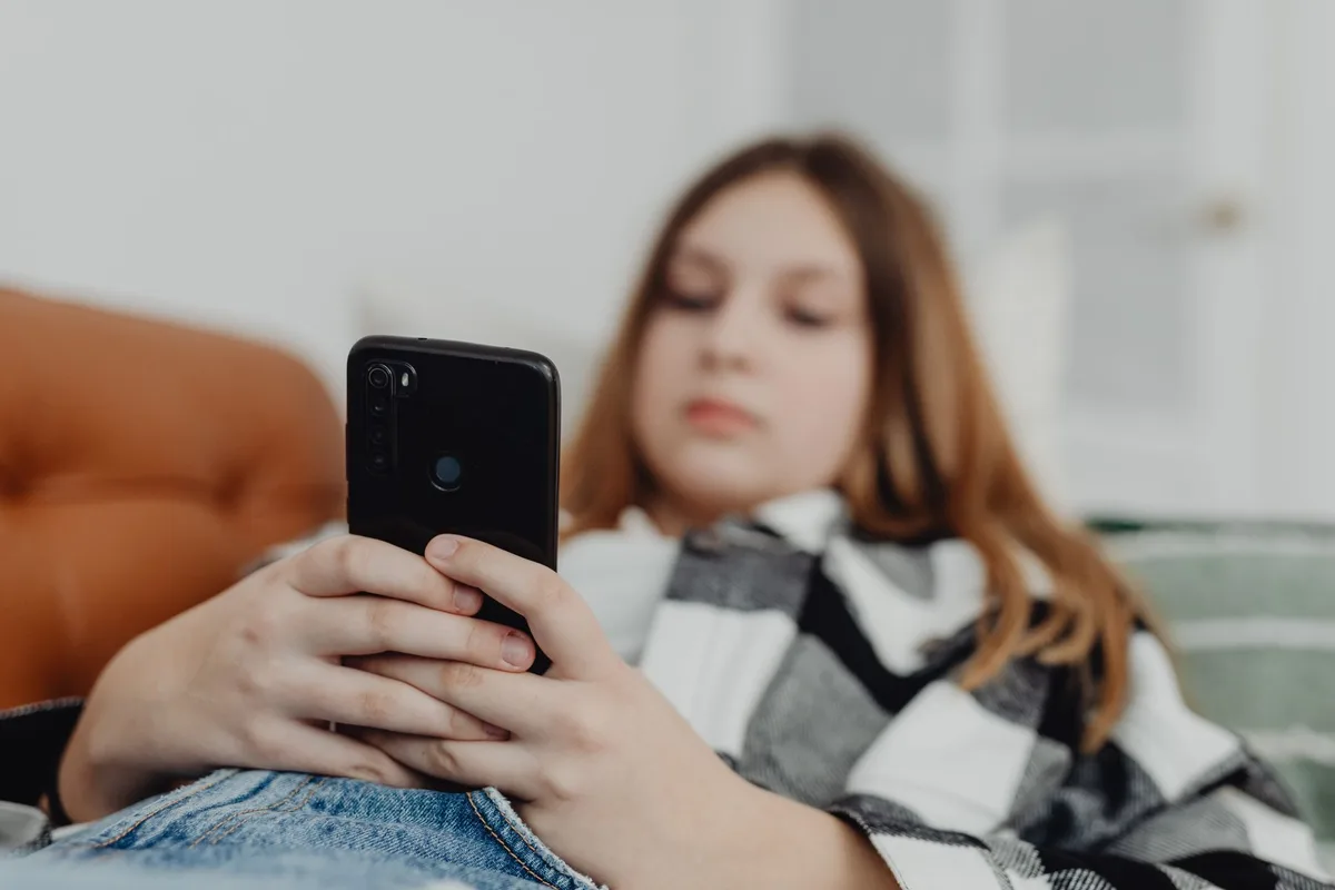 Adolescente com smartphone, mostrando controlos de tempo de utilização