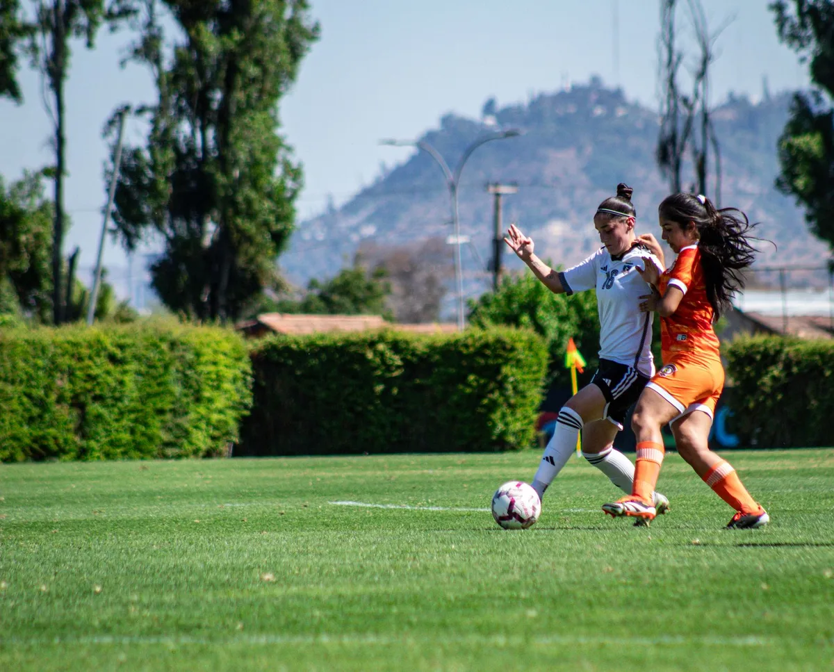 Jovens jogadoras de futebol feminino em ação durante um jogo oficial num estádio