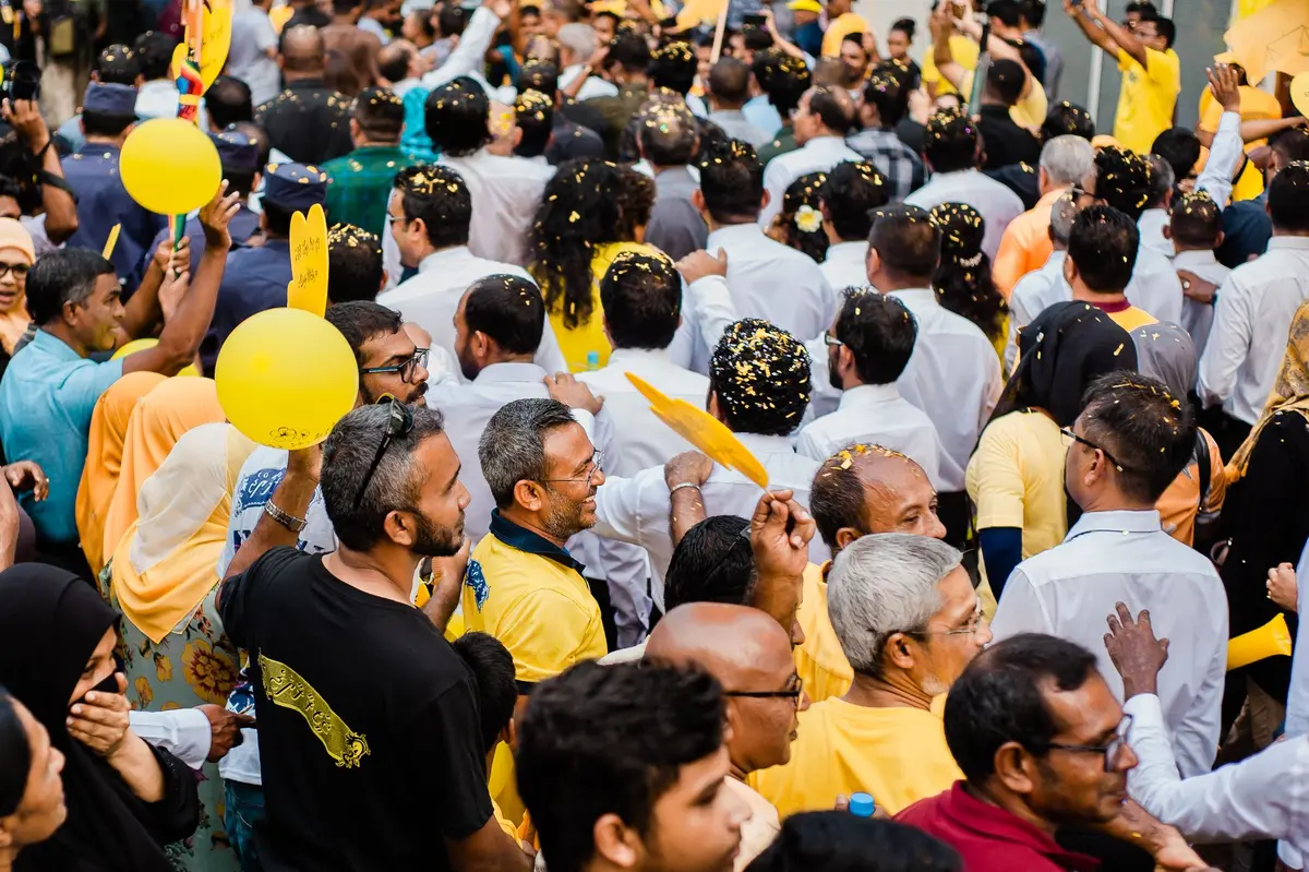 Multidão em celebração de festa política com discursos e participação de membros do partido