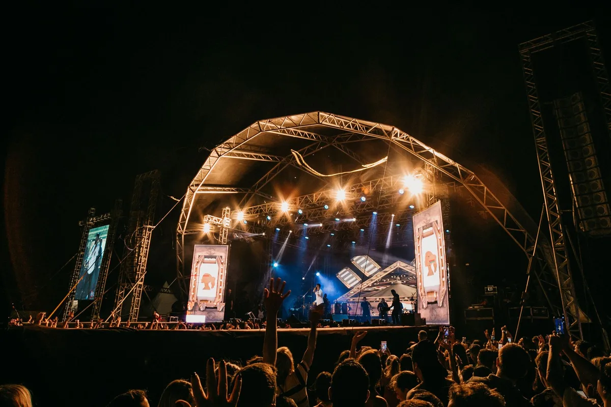 Multidão de pessoas em festival ao ar livre durante concerto ao anoitecer