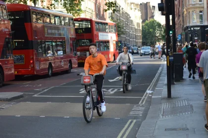Rua urbana com ciclovias, peões e autocarro de transporte público em circulação