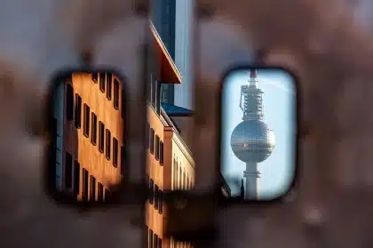 Duas pessoas assistindo televisão numa sala de estar, com luz azulada da tela refletindo no ambiente