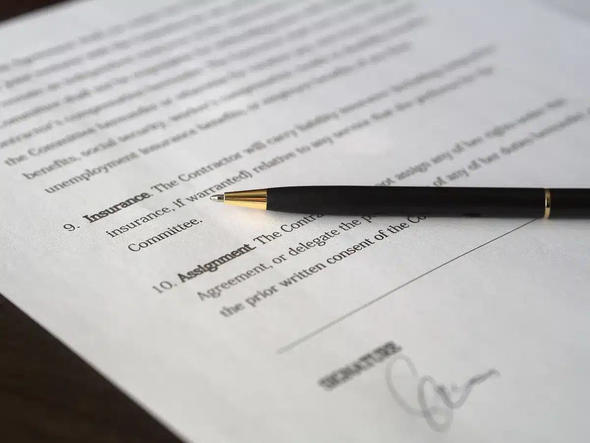 Contrato e documentos sobre mesa com caneta e computador