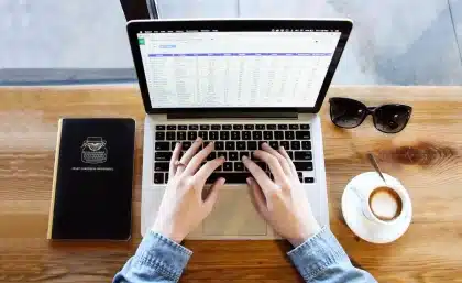 Mãos anónimas sobre documento e portátil numa mesa de escritório governamental minimalista