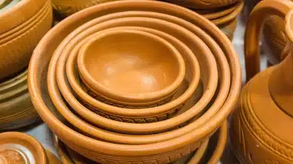 Mãos anónimas de artista sobre mesa com pincéis e esboços