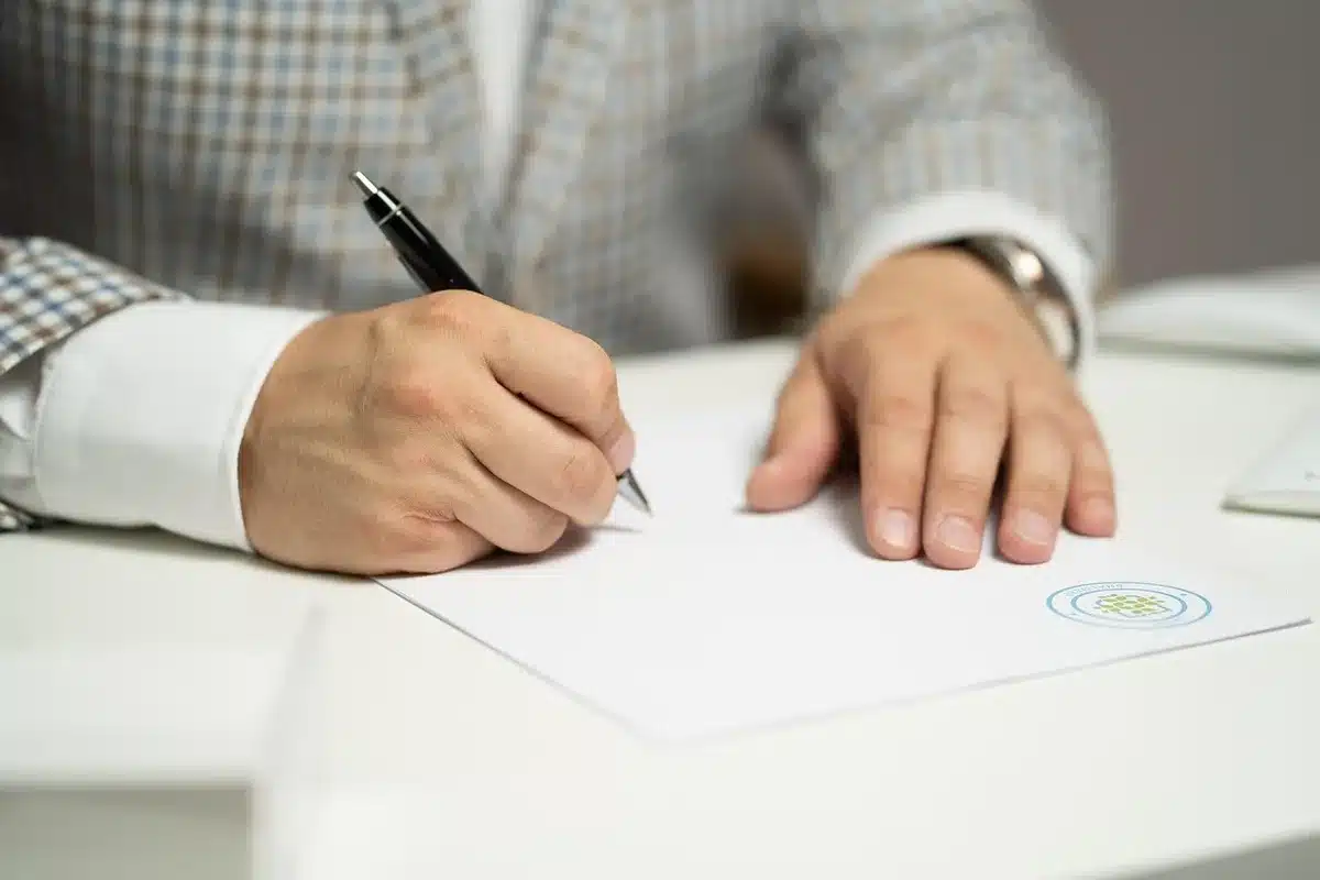 Documentos e mãos ao assinar contrato numa mesa