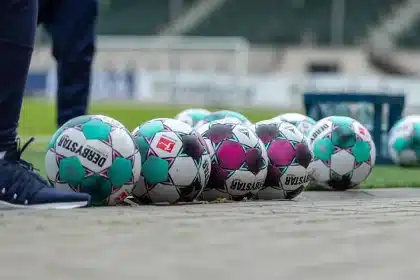 Mãos segurando um bilhete e um cachecol no estádio, ambiente de expectativa