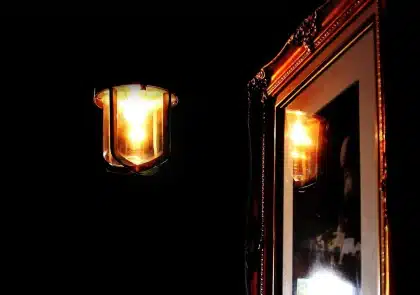 Recortes de jornais antigos e páginas impressas expostos numa parede de galeria com iluminação suave