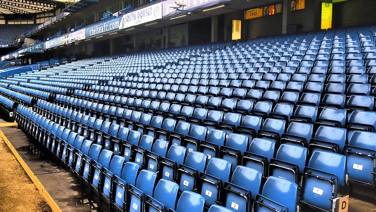 Vista exterior do Etihad Stadium com bancadas e público distante