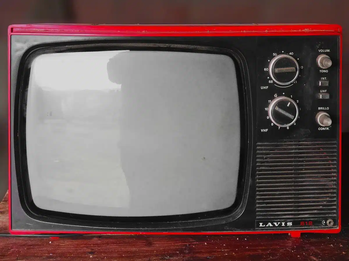 empty stage with a lone vintage television on a small table, soft spotlight, dark auditorium seats in the background