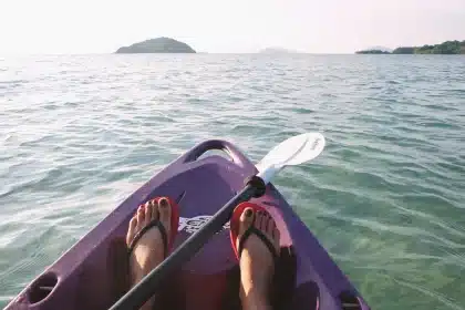 Atleta em canoagem de competição com remo em kayak, em água calma durante treino ou prova