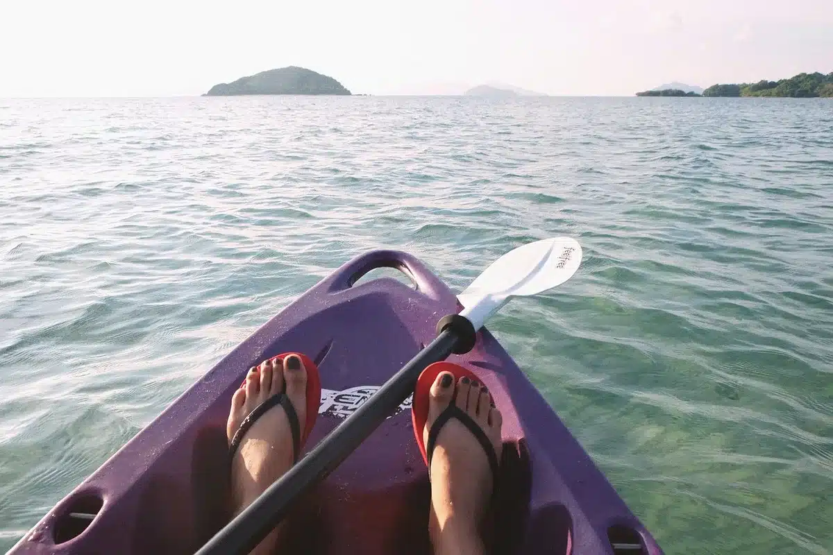 Atleta em canoagem de competição com remo em kayak, em água calma durante treino ou prova