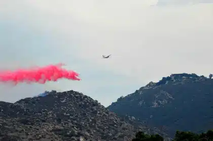 Bombeiros combatem incêndio intenso à noite com chamas visíveis ao fundo