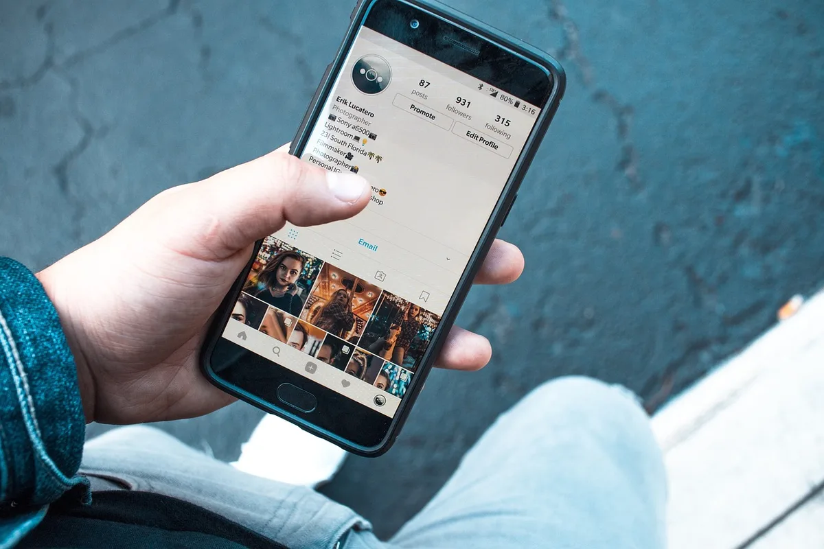 Ecrã de smartphone congelado com dedo próximo ao botão de reinício em ambiente escuro