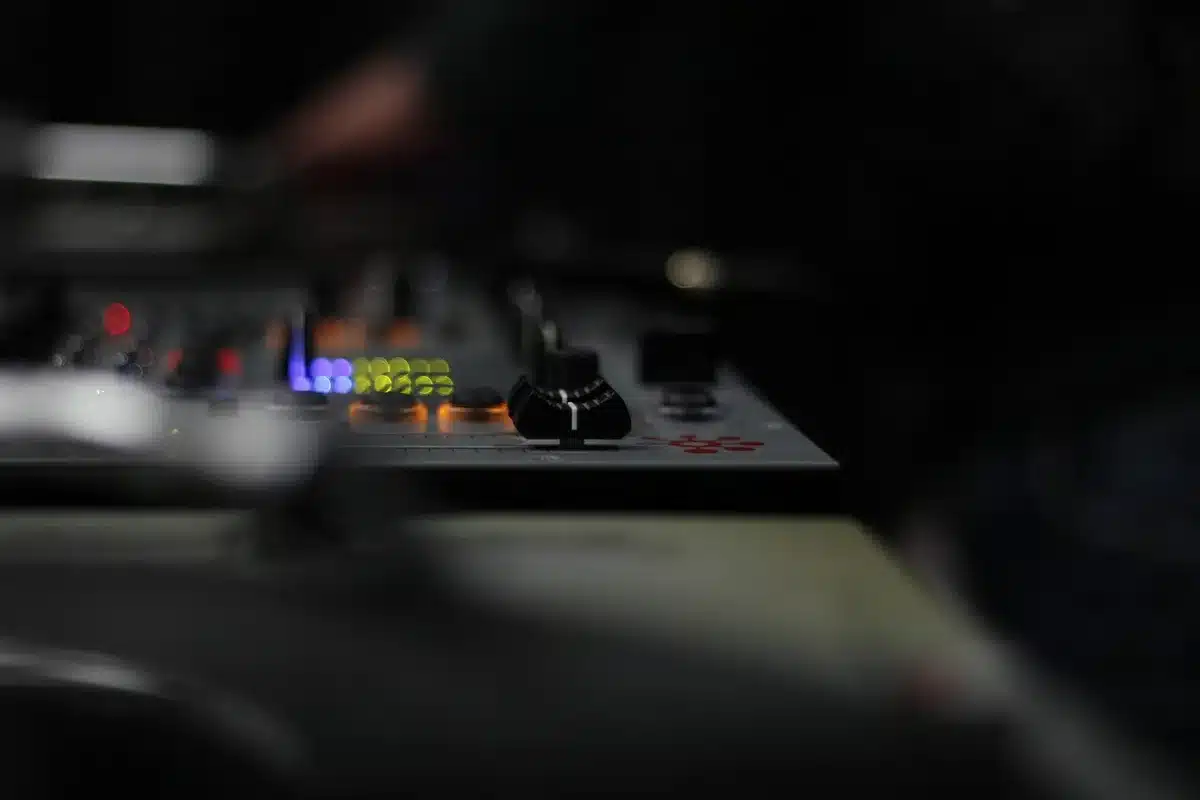 Pista de dança com coluna de som e gira-discos num espaço industrial, público anónimo em silhueta