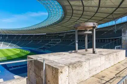 Estádio vazio com camisolas genéricas e jornal na bancada, atmosfera de incerteza