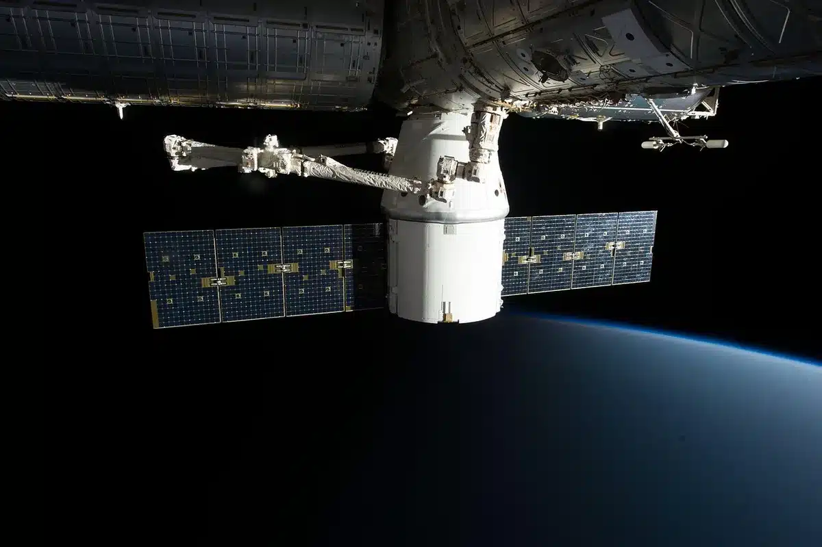Satélite em órbita no espaço, com a Terra ao fundo e atmosfera visível