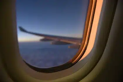 Interior de um avião com janelas mostrando a paisagem urbana abaixo e assentos vazios