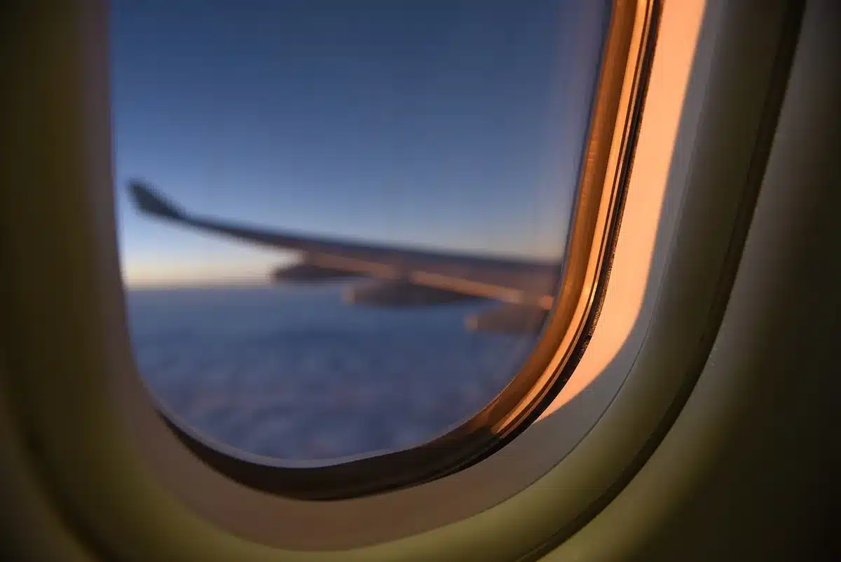 Interior de um avião com janelas mostrando a paisagem urbana abaixo e assentos vazios