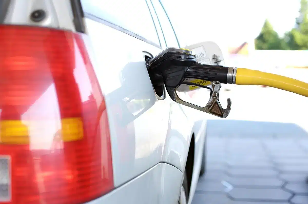 Caixa com preços de combustíveis e fila de carros na estação