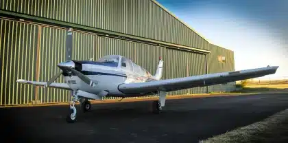 Avião de fuselagem larga em hangar de produção com técnicos a inspecionarem detalhes da aeronave