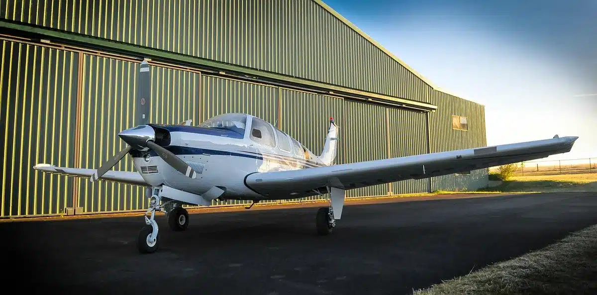 Avião de fuselagem larga em hangar de produção com técnicos a inspecionarem detalhes da aeronave