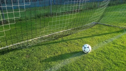 Jogadores em confronto durante partida de futebol com adeptos nas bancadas