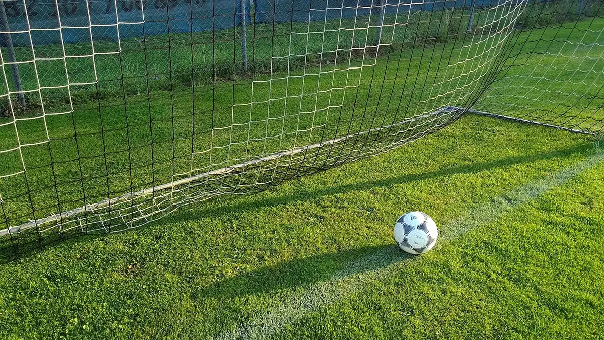 Jogadores em confronto durante partida de futebol com adeptos nas bancadas