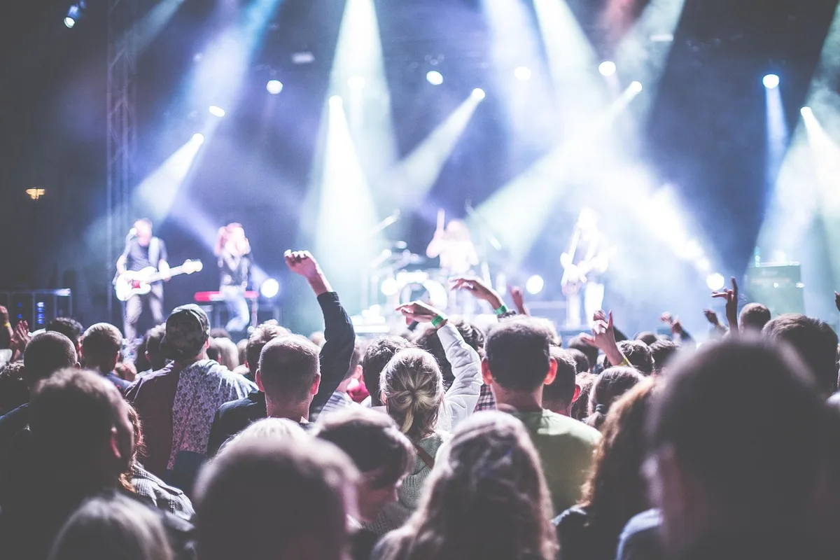 Jovens de diferentes idades reunidas num evento ao ar livre com atividades de desporto e música
