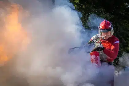 Bombeiros em equipamento de proteção a combater incêndio florestal com fumo e chamas