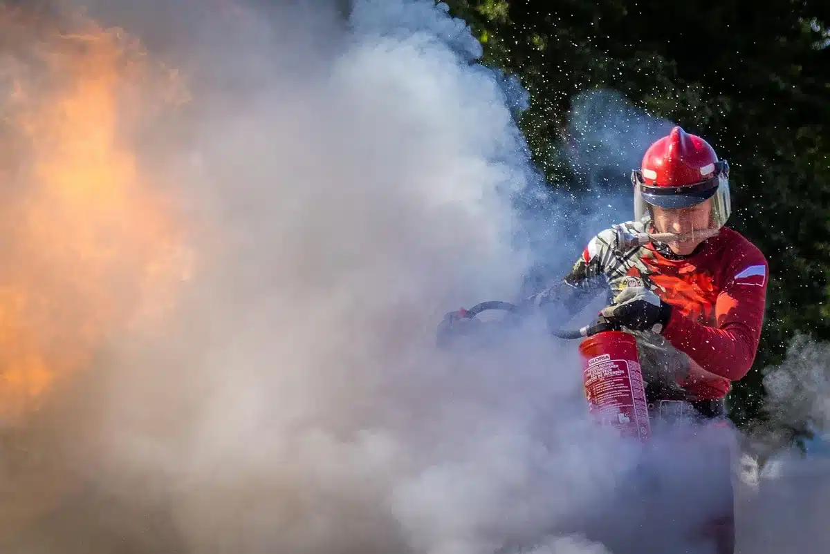 Bombeiros em equipamento de proteção a combater incêndio florestal com fumo e chamas