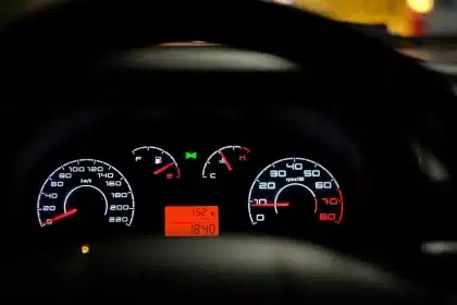 Estrada alpina com carro ao longe e painel de navegação num ecrã de automóvel
