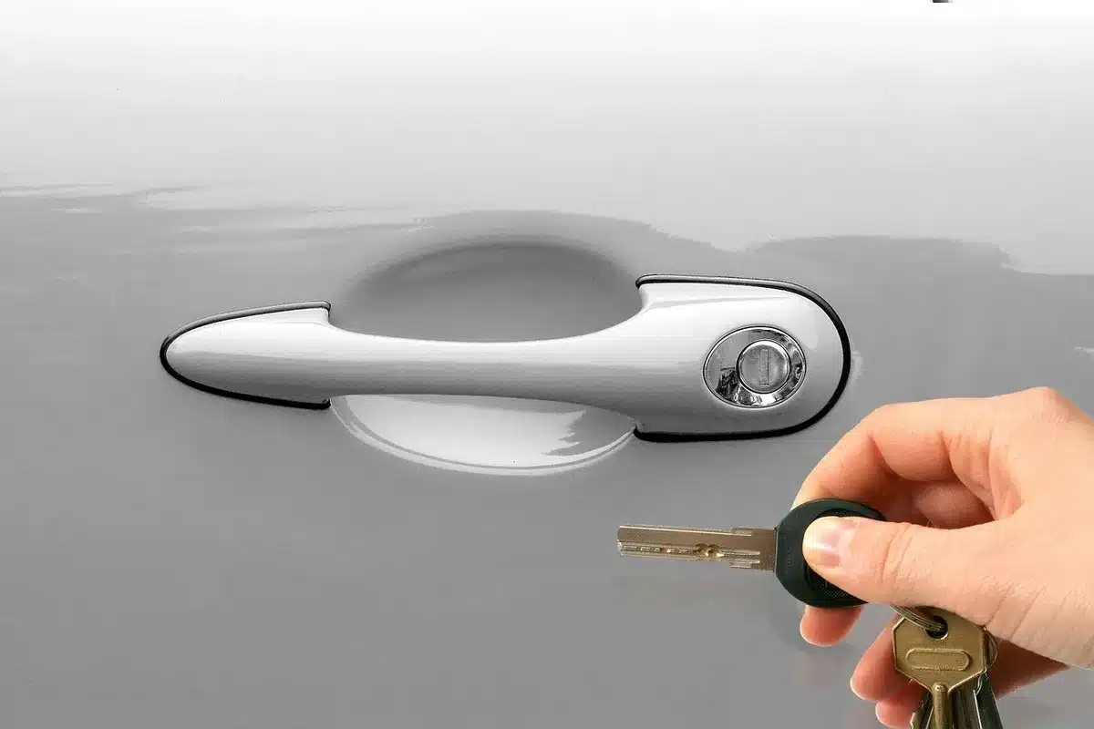 Anonymous silhouette of a person holding a key fob near an apartment door, face obscured