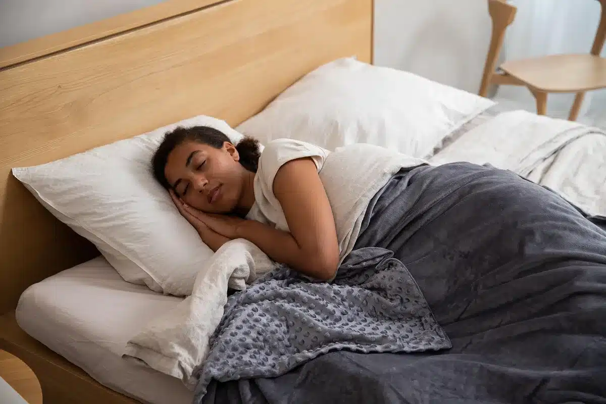 A folded stack of unbranded pink microfibre bed sheets with a subtle zigzag texture, placed on a plain wooden table, small care-label visible but unreadable