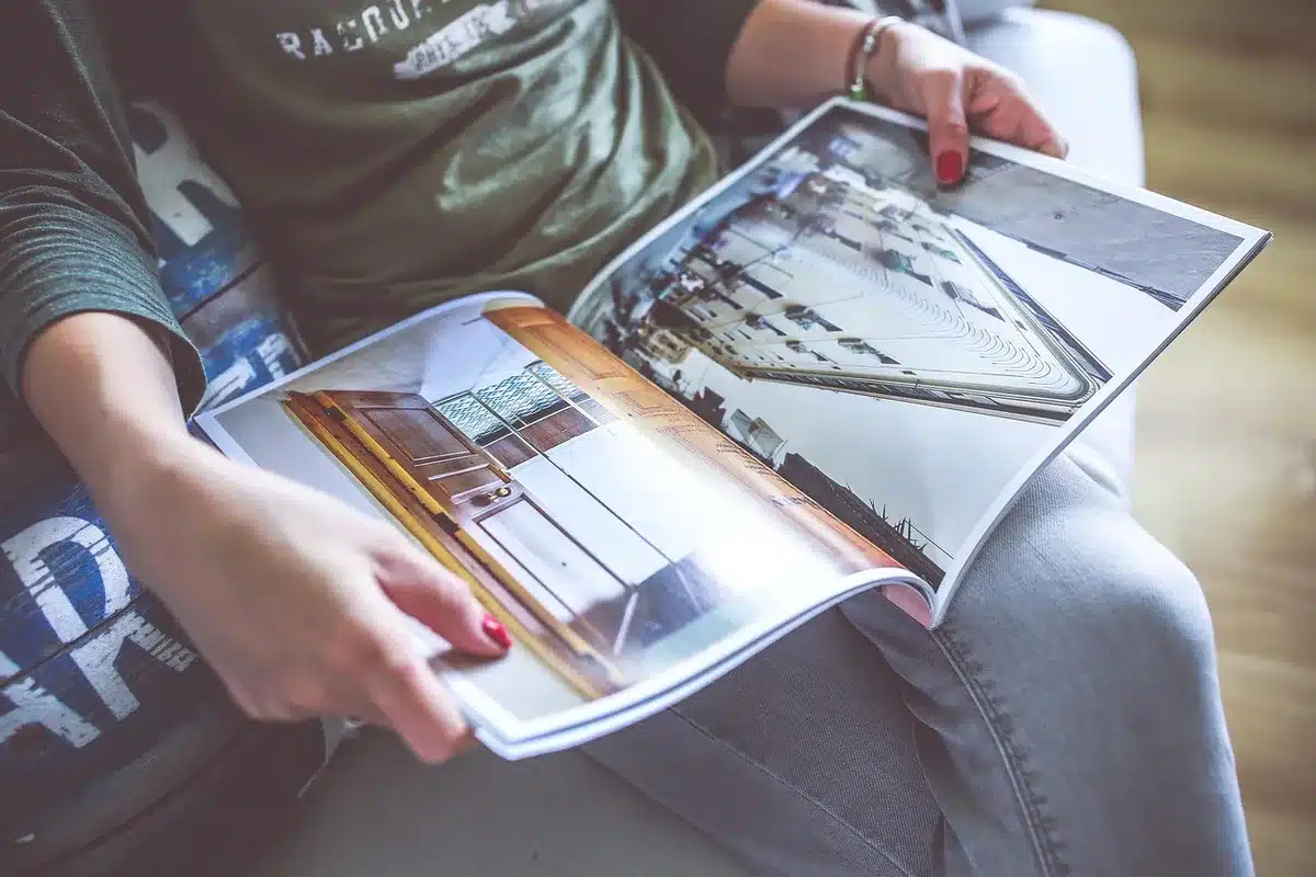 Close-up of an unbranded wooden tabletop with a decorative vase and an anonymous catalog brochure titled "home" out of focus