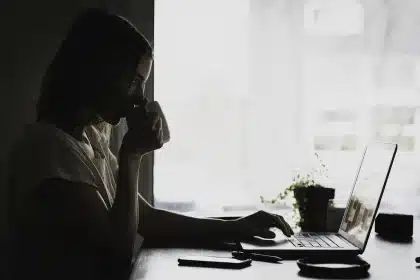 Mesa com gráficos económicos e silhueta de pessoa lendo notas num escritório