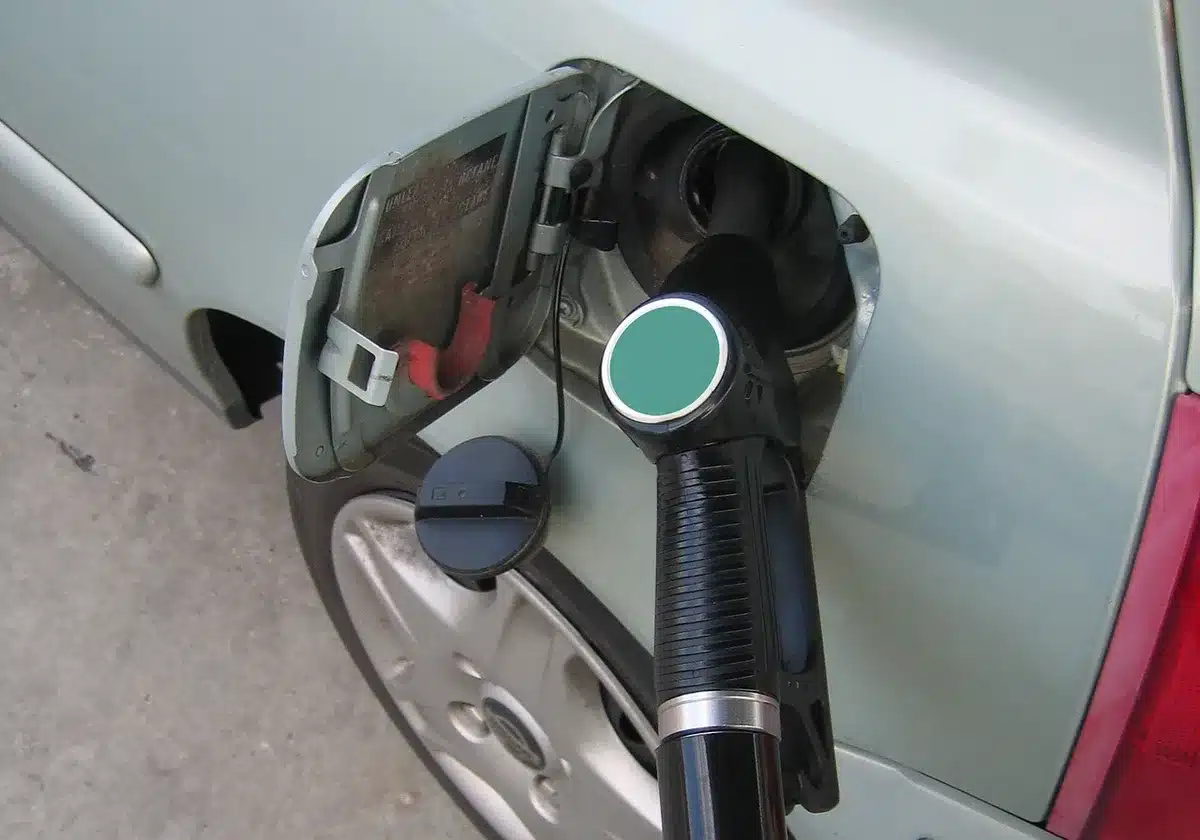 An anonymous close-up of a generic vehicle's rear with an unbranded small nozzle rigged near the bumper, workshop background ambiguous