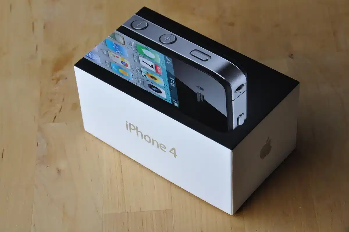 Empty retail shelf with stacked unbranded smartphone boxes and one open box revealing a generic handset