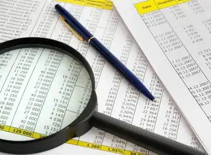 Relatório financeiro aberto com mãos anónimas a apontar para tabelas e uma calculadora
