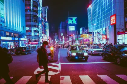 Rua nocturna com luzes neon, palmeiras e um carro descapotável ao longe