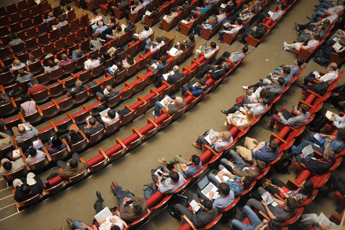 Wide shot of an empty small theatre auditorium, rows of unbranded seats and a dimly lit screen, suggestion of upcoming screenings on the stage