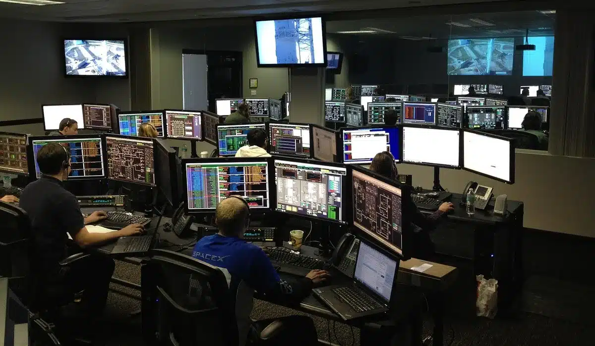 Sala de controlo de televisão antiga com técnicos e painéis