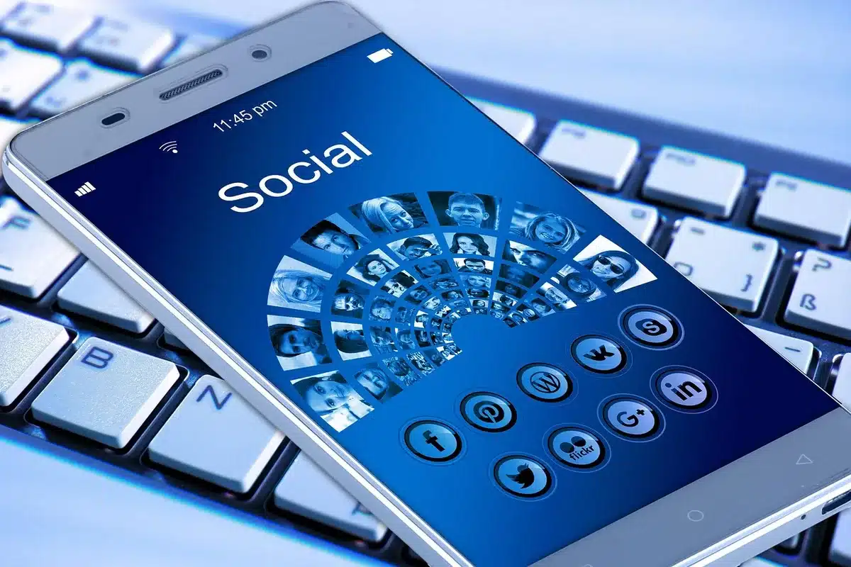 Close-up of an anonymous hand holding a smartphone showing a generic location icon; the background is a blurred café interior