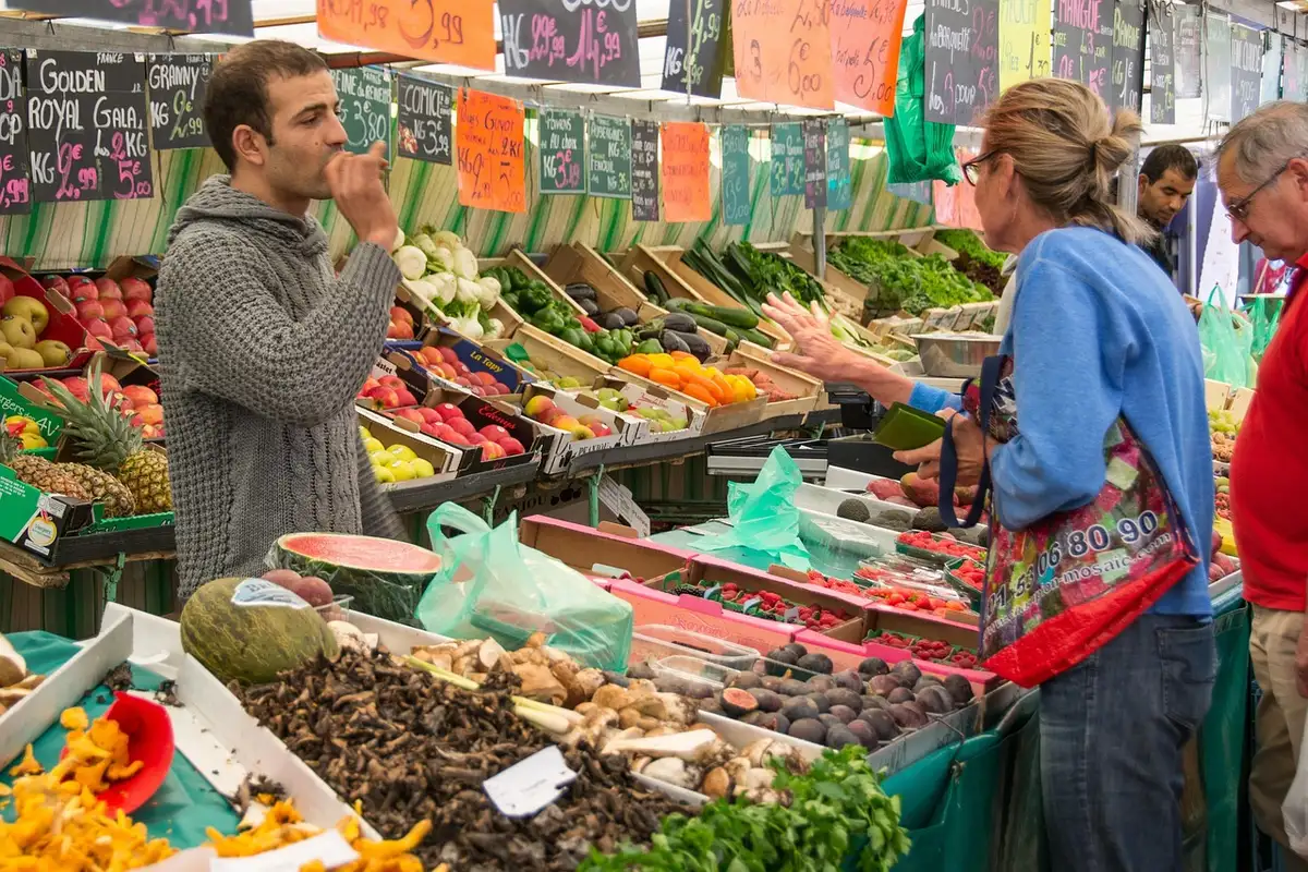 Fornecedores locais com sacos de farinha e fruteiras num mercado